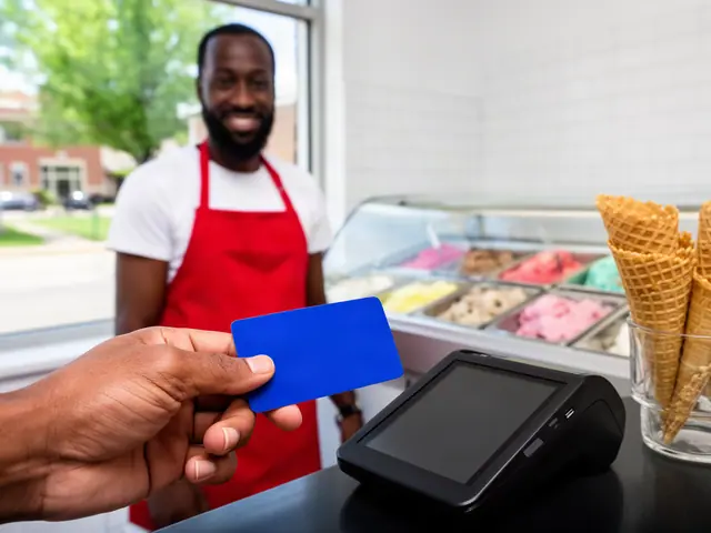 A customer taps a card on a counter terminal at a small neighborhood ice-cream parlor.